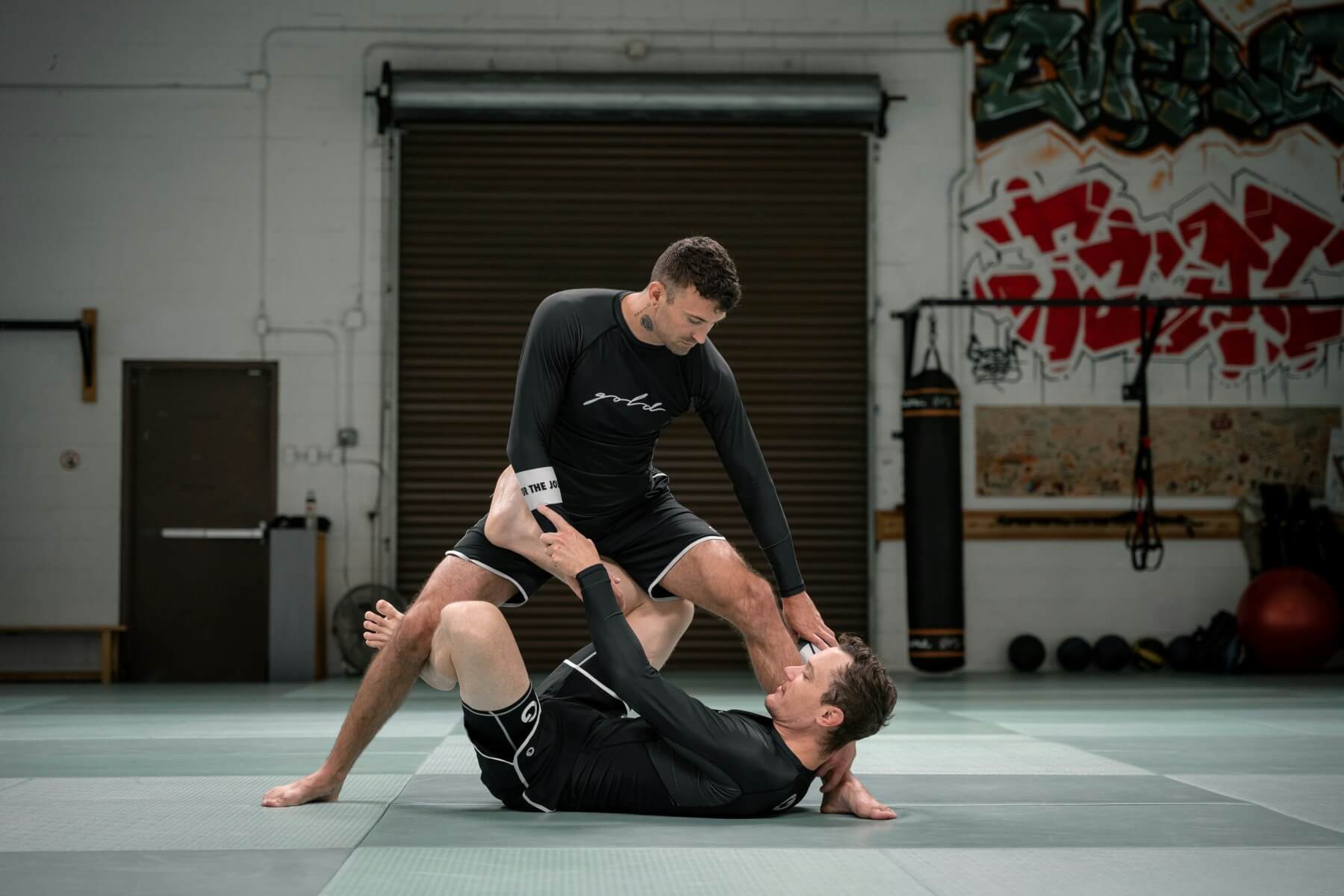 Doi sportivi exersând tehnici de BJJ